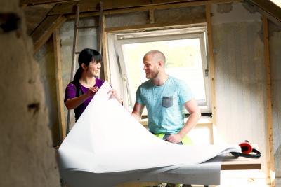 A man and a woman smiling while pasting wallpaper
