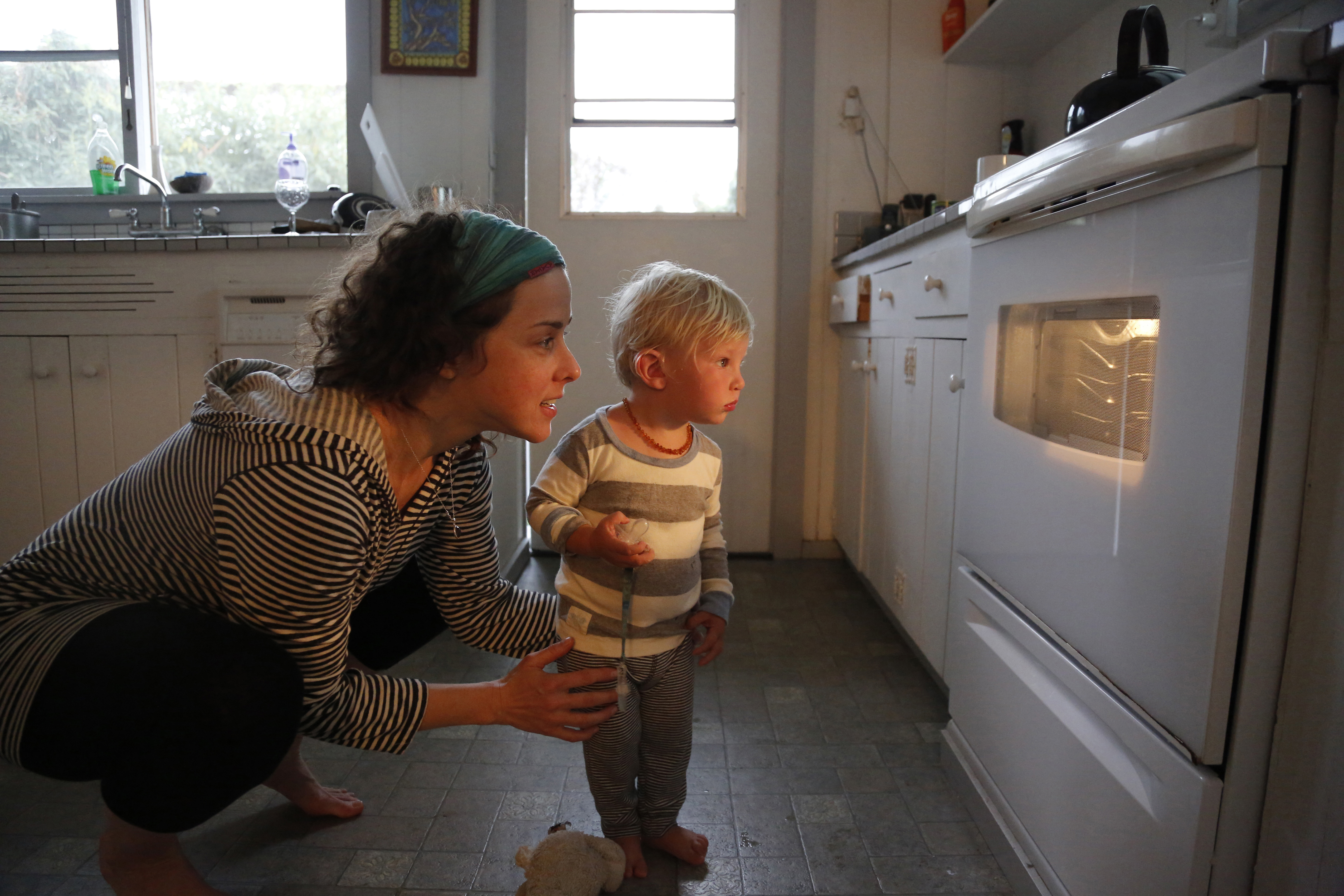 Mother and child looking at food cooking in their oven