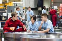 Three factory workers in workspace talking.