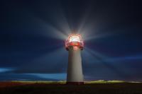Lighthouse List-West on Sylt with lightbeams at upcoming night.