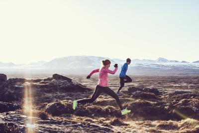 Image of two people out for a run in a remote area with snow covered hills in the background