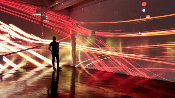 839223960 Young man looking at abstract city landscape being projected in a gallery space