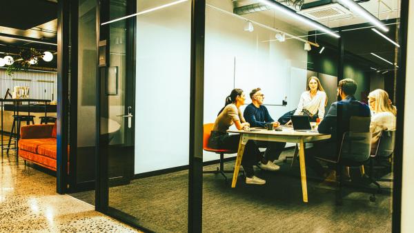 Team of businesspeople having a meeting in a b... Team of diverse businesspeople having a meeting in a transparent boardroom. Group of business professionals having a discussion during a briefing. Colleagues collaborating on a new project.