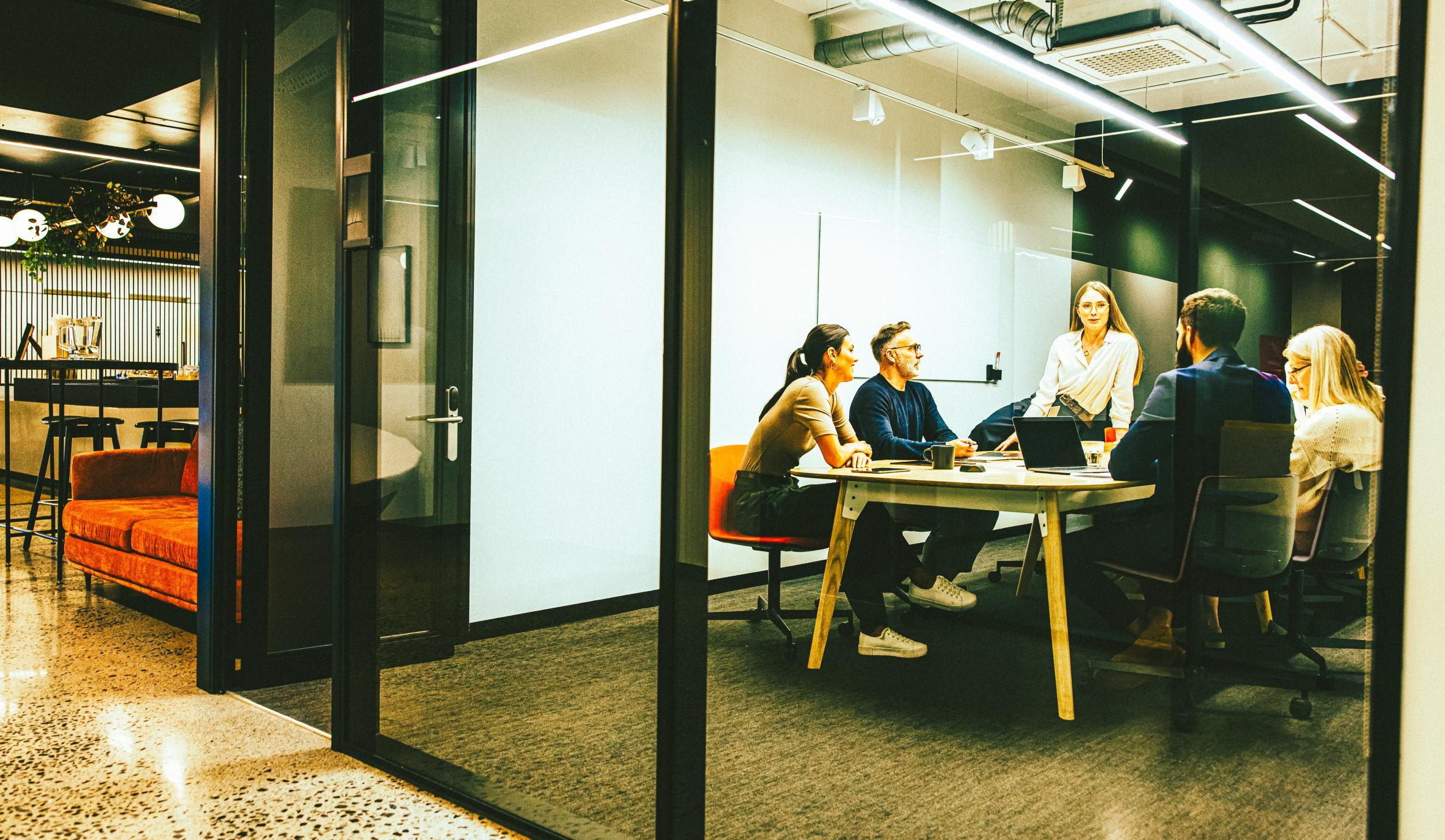 Team of diverse businesspeople having a meeting in a transparent boardroom. Group of business professionals having a discussion during a briefing. Colleagues collaborating on a new project.